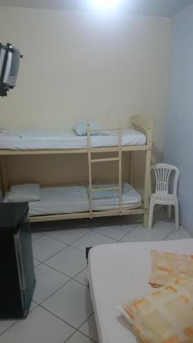 a room with a bunk bed and a chair at Pousada Portal da Ilha in Itaoca