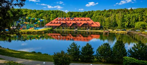 an amusement park with a building and a pond at Hotel Gorzelanny - basen , jacuzzi , sauna sucha, parowa w cenie pobytu! in Pokrzywna