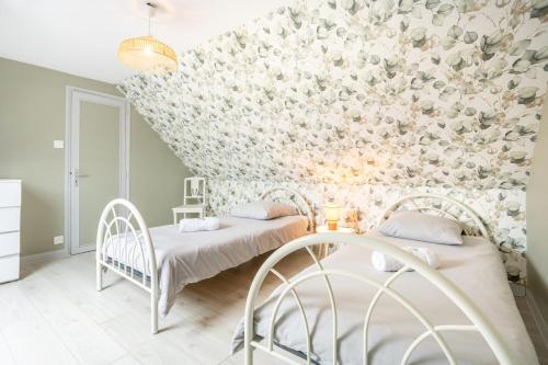 two beds in a room with a floral wall at Gîte Ty Traon piscine partagée in Ergué-Gabéric