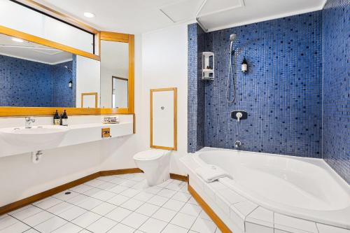 a bathroom with a tub and a toilet and a sink at Quality Hotel Lincoln Green in Auckland