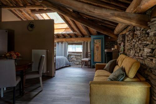 a living room with a couch and a stone wall at Little Chariot in Monastero di Lanzo