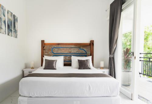 a bedroom with a large bed with a wooden headboard at THE SANDS LOMBOK in Mangsit