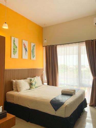 a bedroom with a bed with orange walls and a window at Omah Manis in Yogyakarta