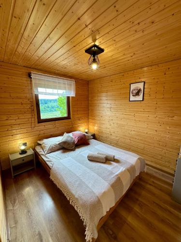 a bedroom with a bed in a wooden cabin at Siedlisko Wataha 721-140-600 in Wołkowyja