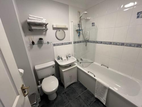 a bathroom with a toilet and a tub and a sink at Yarg Cottage in Falmouth