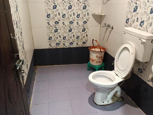 a bathroom with a toilet and a bucket in it at Jai Shri Badri in Badrinath