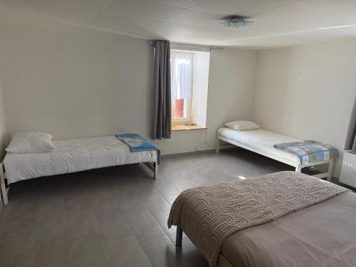 a room with two beds and a window at Pâquier 3 in Saint-Sulpice