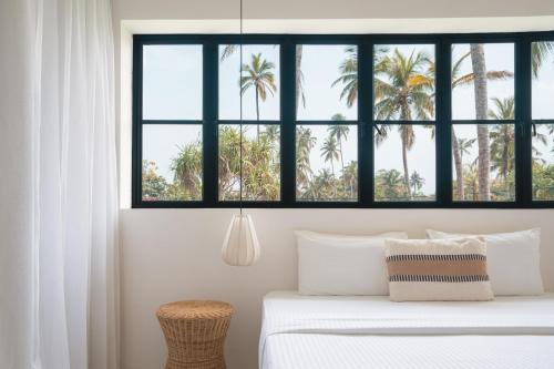 a bedroom with a bed with palm trees in the background at Air Villa in Ahangama