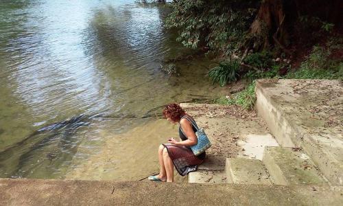 a woman sitting on the steps by the water at Don Santiago Guesthouse Downtown in San Ignacio