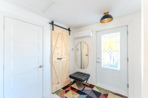 a stool in a hallway with a door and a window at Pretty Little House in Saguenay