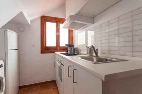 a white kitchen with a sink and a refrigerator at My Little Loft in the Heart of Seville in Seville