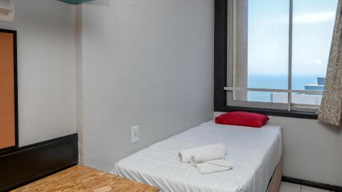a small bedroom with a white bed and a window at Seaboard Apart Hotel in Durban