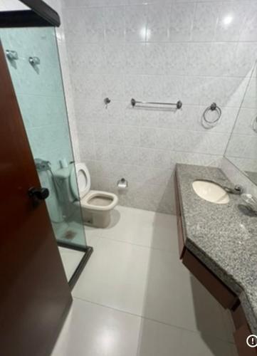 a bathroom with a toilet and a sink and a mirror at Praia da costa vista total in Vila Velha