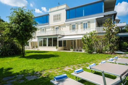 an exterior view of a building with a yard with lounge chairs at Villa Guidi 10 Emma Villas in Milano Marittima