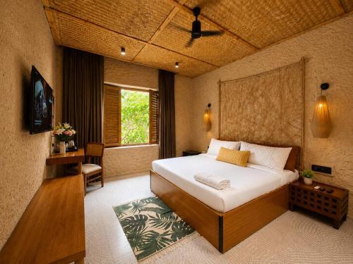 a bedroom with a bed and a desk and a window at The Ark Resort in Bhopal