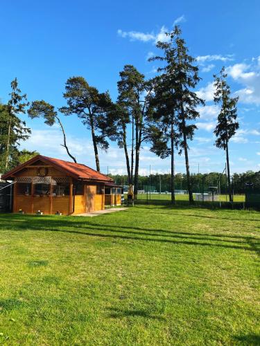 a building in a field with trees in the background at Sternik Dom gościnny in Niechorze