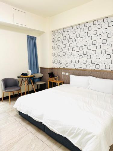 a bedroom with a white bed and a wall at 倆倆民宿 in Donggang