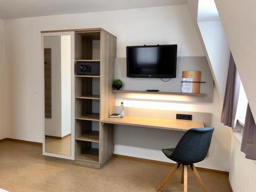 a room with a desk with a television and a chair at Zenntaler Hof in Neuhof an der Zenn