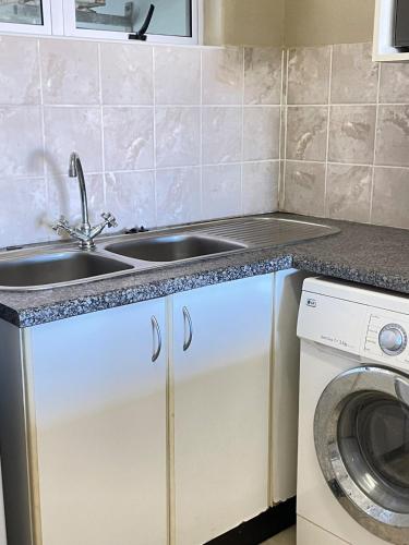 a kitchen with a sink and a washing machine at Stay Joy coastal in Margate