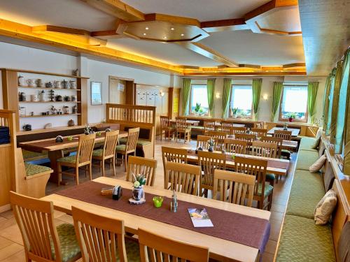 a restaurant with wooden tables and chairs and windows at Zenntaler Hof in Neuhof an der Zenn