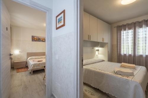 a small bedroom with two beds and a bathroom at L'Aurora Porto Torres in Porto Torres