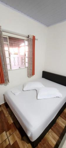 a large white bed in a room with a window at Casa Benta in Aparecida