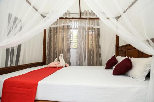 - une chambre dotée d'un grand lit blanc avec un oiseau assis dans l'établissement Wayside Mirissa, à Mirissa