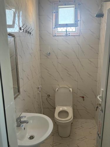 a white bathroom with a toilet and a sink at Modern studio apartment in Mogadishu