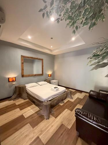 a bedroom with a bed and a mirror and a couch at Topinn Hotel in Ban Lat Krachaeng