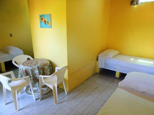 a room with two beds and a table and chairs at Pousada Sol Nascente in Cumuruxatiba