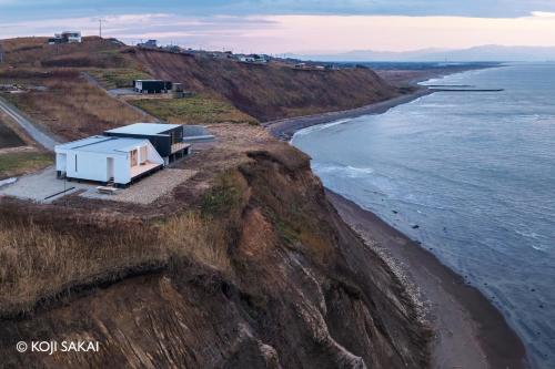 a house on a cliff next to the ocean at Cliff House MORAI 2 in Ishikari