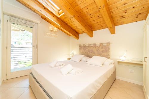 a bedroom with a large white bed with wooden ceilings at The A-LINE Lake COMO view apt A with pool & garage in Tremezzo