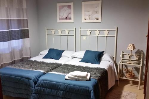 ein Schlafzimmer mit zwei Betten mit blauen Kissen in der Unterkunft El Rincón de Gredos in Navaluenga