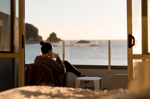 a woman sitting in a chair looking out at the ocean at Tasman Holiday Parks - Hahei Beach in Hahei