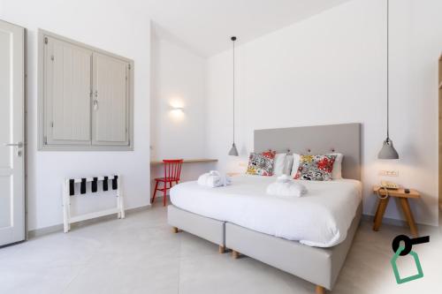 a white bedroom with a large white bed with two pillows at Hotiday Santorini Oia in Oia