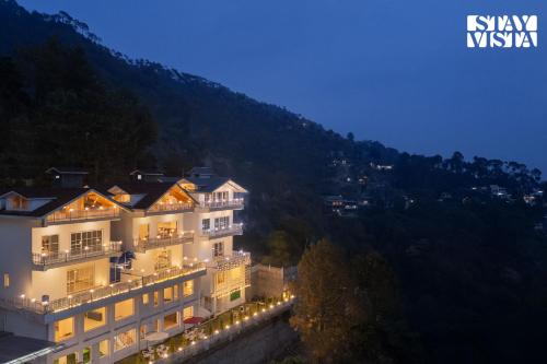 a large building with lights on it at night at StayVista at IRIS with Outdoor Pool & Bonfire in Dagshai
