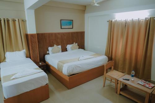a hotel room with two beds and a table at Nova Saara Palace in Kannur