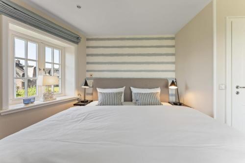 a bedroom with a large white bed and two windows at Haus Meerblick in Rantum