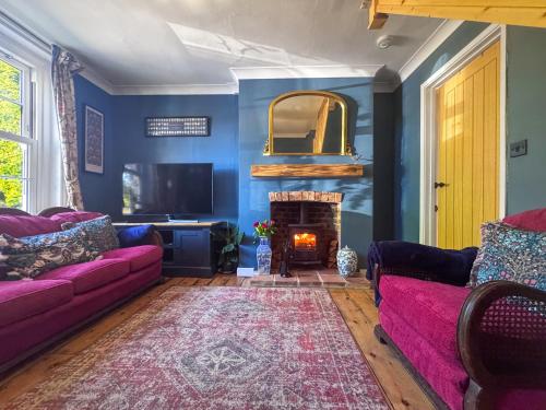 a living room with a purple couch and a fireplace at Little Tern in Snettisham