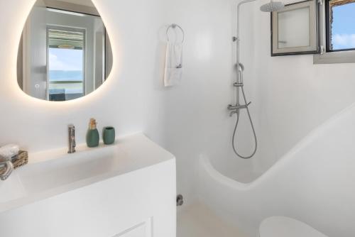 a white bathroom with a sink and a mirror at Your private Mykonos Villa in Kalafatis