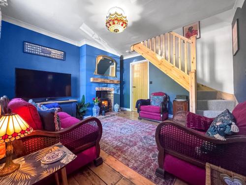 a living room with purple furniture and a staircase at Little Tern in Snettisham