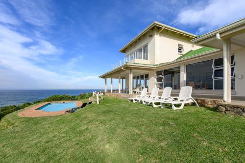 a house with a yard with chairs and a swimming pool at Shabby View Beach House in Southbroom