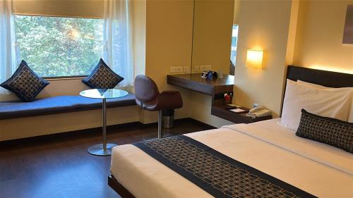 a hotel room with a bed and a window at Marasa Sarovar Portico -Rajkot in Rajkot