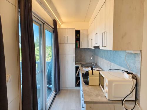 a kitchen with white cabinets and a large window at GF Mobilehomes Kroatien in Drage