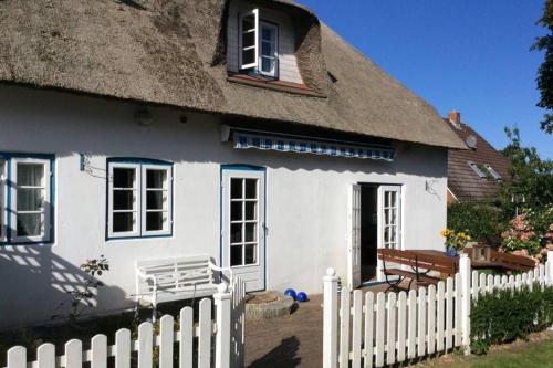 a white house with a thatched roof and a fence at Kapitänshaus, Hausteil in Oevenum