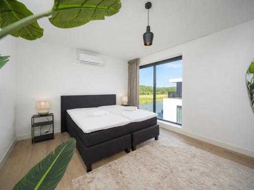 a bedroom with a bed and a large window at Harderwold Villa Resort XL in Zeewolde