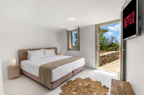 a bedroom with a bed and a sliding glass door at Your private Mykonos Villa in Kalafatis