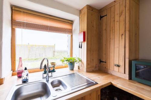 a kitchen with a sink and a window at The Workshop- Eco Cottage by the Coastal Path in Goodwick