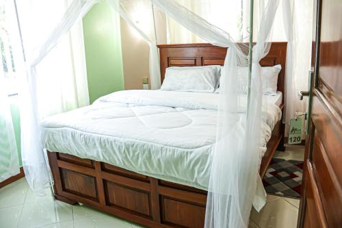 a bedroom with a canopy bed with white sheets at JK Maasai Hotel in Wasso