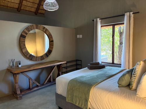 a bedroom with a bed and a mirror and a window at Shiandi Cottage in Hoedspruit